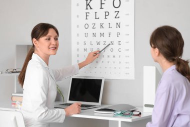 Kadın göz doktoru klinikte hastanın gözlerini kontrol ediyor.