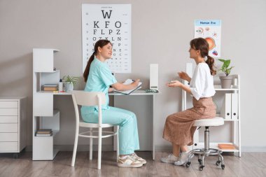 Klinikte hastayla birlikte çalışan kadın göz doktoru.