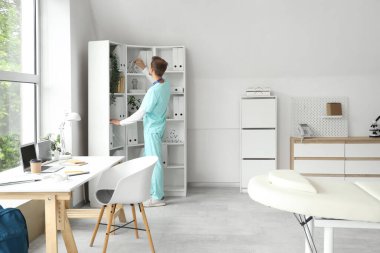 Erkek stajyer klinikteki raftan moleküler modeli alıyor.