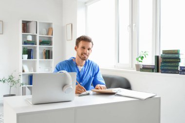 Kütüphanedeki masada çalışan erkek stajyer doktor.