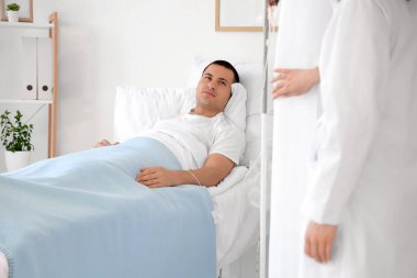 Erkek hasta hastane koğuşunda doktorla yatakta yatıyor.