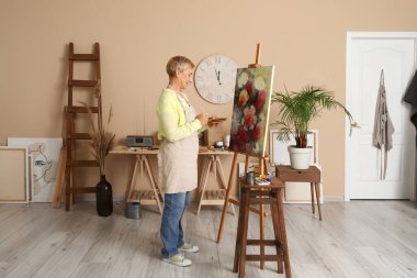 Atölyede resim yapan olgun bir kadın sanatçı.