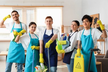Ofisinde temizlik malzemeleri olan bir grup genç hademe.