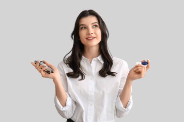 Beyaz arka planda kontakt lensler için gözlük ve kap tutan mutlu, genç bir kadın.