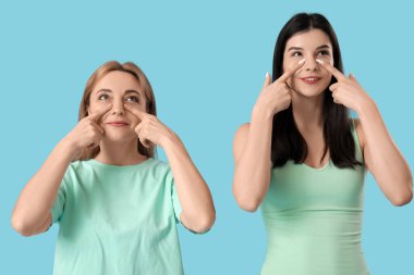 Güzel, mutlu kadınlar mavi arka planda yüz geliştirme egzersizi yapıyorlar.