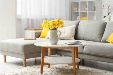 Oturma odasındaki kahve masasındaki sürahide nergis çiçeği