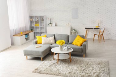 Şık oturma odasının içinde kanepe ve nergis çiçekli kahve masası var.