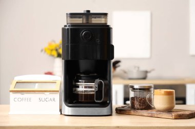 Modern kahve makinesi, fasulye ve bir bardak espresso mutfaktaki ahşap masada.
