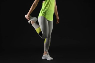 Siyah arka planda taytlı genç bir kadın.