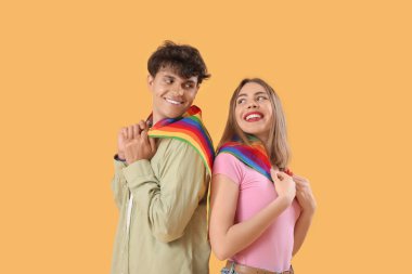 Sarı arka planda LGBT bayrakları olan genç çift