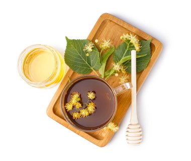 Beyaz arka planda yapraklı, çiçekli ve bal kavanozlu ıhlamur çayı.