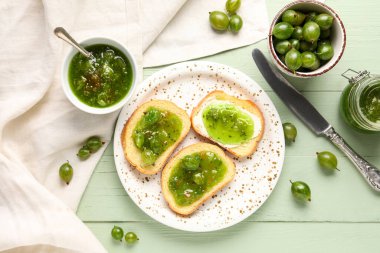 Yeşil ahşap arka planda bektaşi üzümü reçelli lezzetli sandviçler.