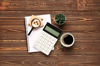 Hesap makinesi, ev modeli, bir fincan kahve, büyüteç ve ahşap arka planda ev bitkisi. İpotek kavramı