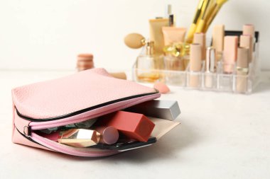 Farklı kozmetik ürünleri ve hafif arka planda cep telefonu olan çanta