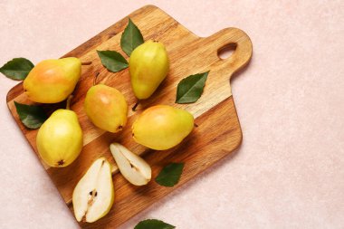 Tahta tahta tahta, taze armutlar ve pembe arka planda yapraklar.