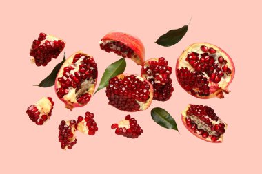 Pembe arka planda taze nar ve yapraklar uçuşuyor.