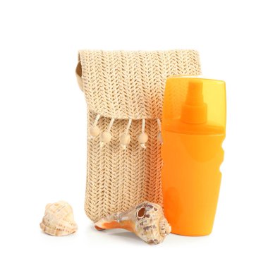 Hasır çantalı bir şişe güneş kremi ve beyaz arka planda izole edilmiş deniz kabukları.