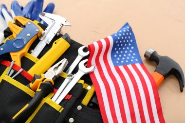 Farklı araçlara sahip kemer ve bej arka planda ABD bayrağı. İşçi Bayramı kutlamaları