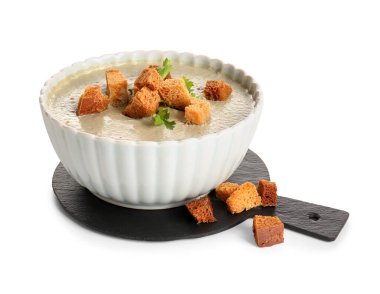 Beyaz arka planda kızarmış ekmeklerle bir kase lezzetli krema çorbası.