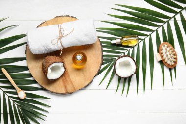 Beyaz ahşap arka planda hindistan cevizi kozmetik yağı ve banyo havlusuyla dekoratif tezgah.