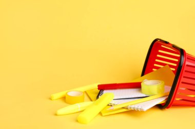 Renk arkaplanında farklı kırtasiye malzemesi olan alışveriş sepeti