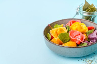 Kaynamış renkli hamur köfteleri ve mavi arka planda ıspanak.