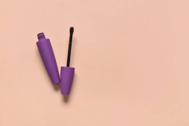 Pembe arka planda mor tüp içinde siyah rimel.