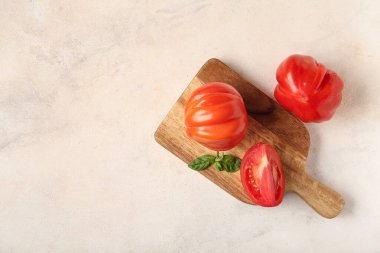 Taze domatesli ahşap tahta ve beyaz arka planda fesleğen.