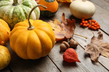 Kahverengi ahşap arka planda balkabağı ve sonbahar yapraklarıyla kompozisyon