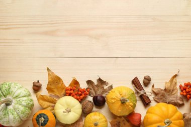 Kahverengi ahşap arka planda balkabağı ve sonbahar yapraklarıyla kompozisyon