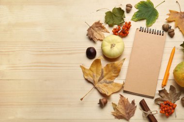 Kahverengi ahşap arka planda defter, balkabağı ve sonbahar yapraklarıyla kompozisyon