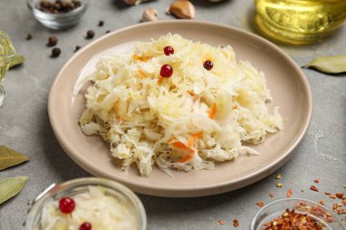 Lezzetli lahana turşulu tabak ve gri arka planda farklı baharatlar.