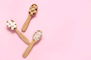 Pembe arka planda farklı tipte şeker içeren kaşıklar