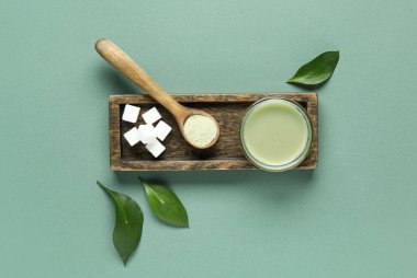 Ahşap tahta üzerinde taze kibrit çayı, toz ve şeker rengi arka planda.