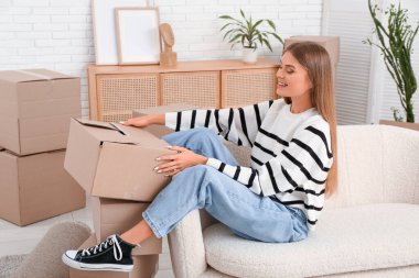 Yeni dairesindeki kanepede oturan karton kutulu güzel genç bayan. Taşınma konsepti