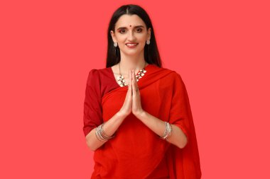 Sari giymiş genç ve güzel bir Hintli kadın kırmızı arka planda dua ediyor. Divaly kutlaması