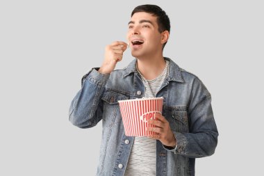 Mutlu genç adam arka planda patlamış mısır yiyor.