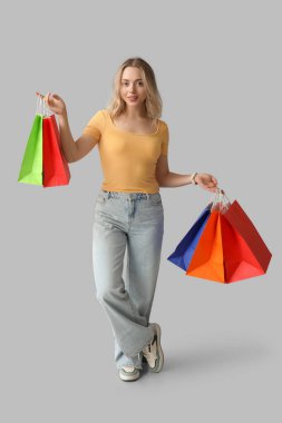 Beyaz arka planda alışveriş torbaları olan genç bir kadın.