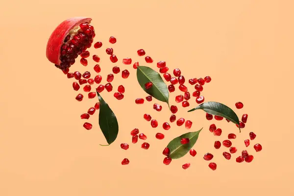 stock image Flying fresh pomegranate with seeds and leaves on orange background