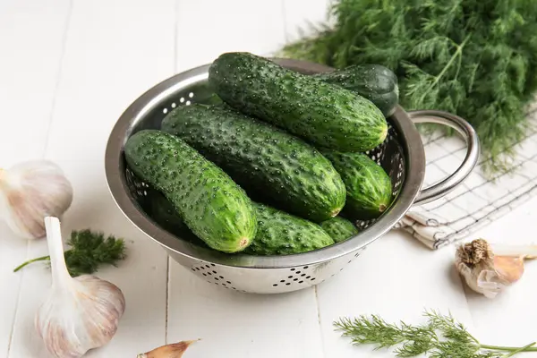 Taze salatalıklı kolander, sarımsak ve dereotu beyaz ahşap arka planda.