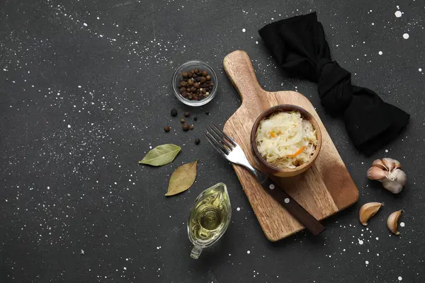 Lezzetli lahana turşulu ahşap tahta tahta ve siyah arka planda farklı baharatlar.