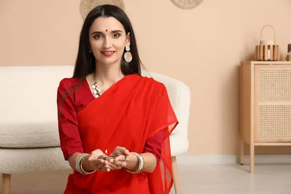 Beautiful young Indian woman in sari with diya lamp at home. Divaly celebration