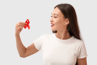 Beyaz arka planda kırmızı kurdeleli güzel bir genç kadın. Dünya AIDS Günü konsepti