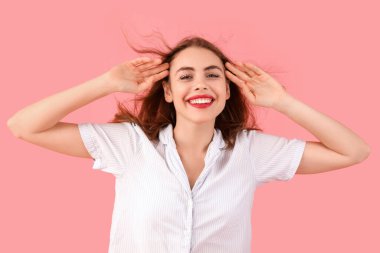 Pembe arka planda pijamalı mutlu genç bir kadının portresi.