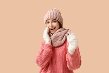 Bej arka planda dekoratif kar taneleri olan şaşırmış genç bir kadın.