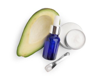 Beyaz arka planda taze avokadosu olan kozmetik ürünleri.