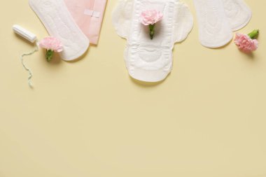 Tamponlu adet pedleri ve sarı arka planda karanfil çiçekleri.