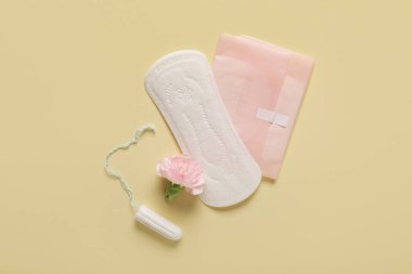 Sarı arka planda tampon ve karanfil çiçekli adet pedleri