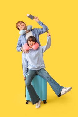 Sarı arka planda pasaportları ve bavulları olan iki genç turist.