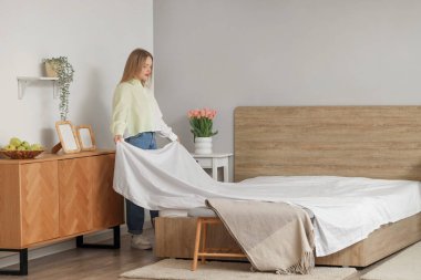 Yatak odasında yatak hazırlayan güzel bir genç kadın.